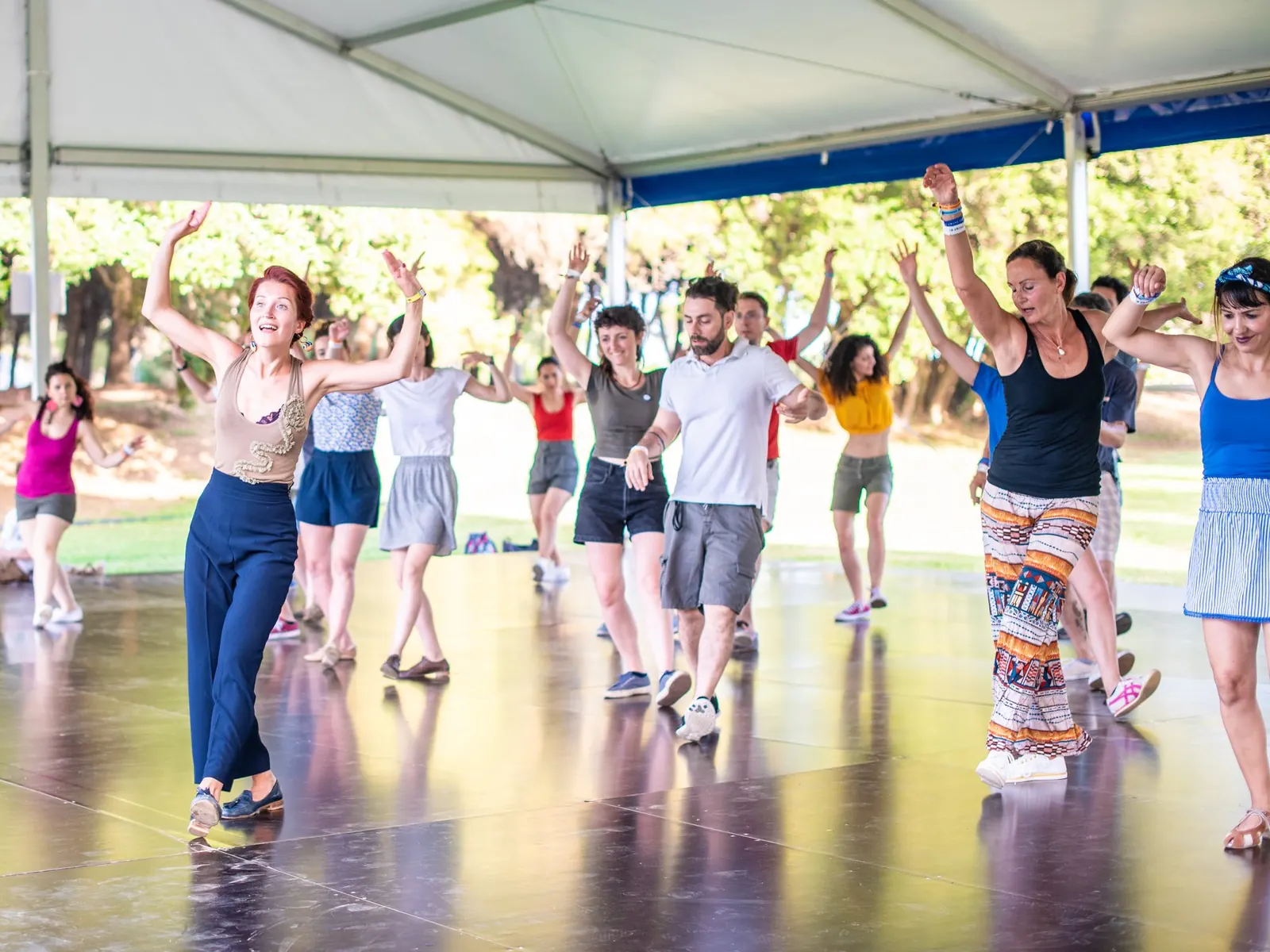 Open-air dance class under the trees: arms up and big smiles